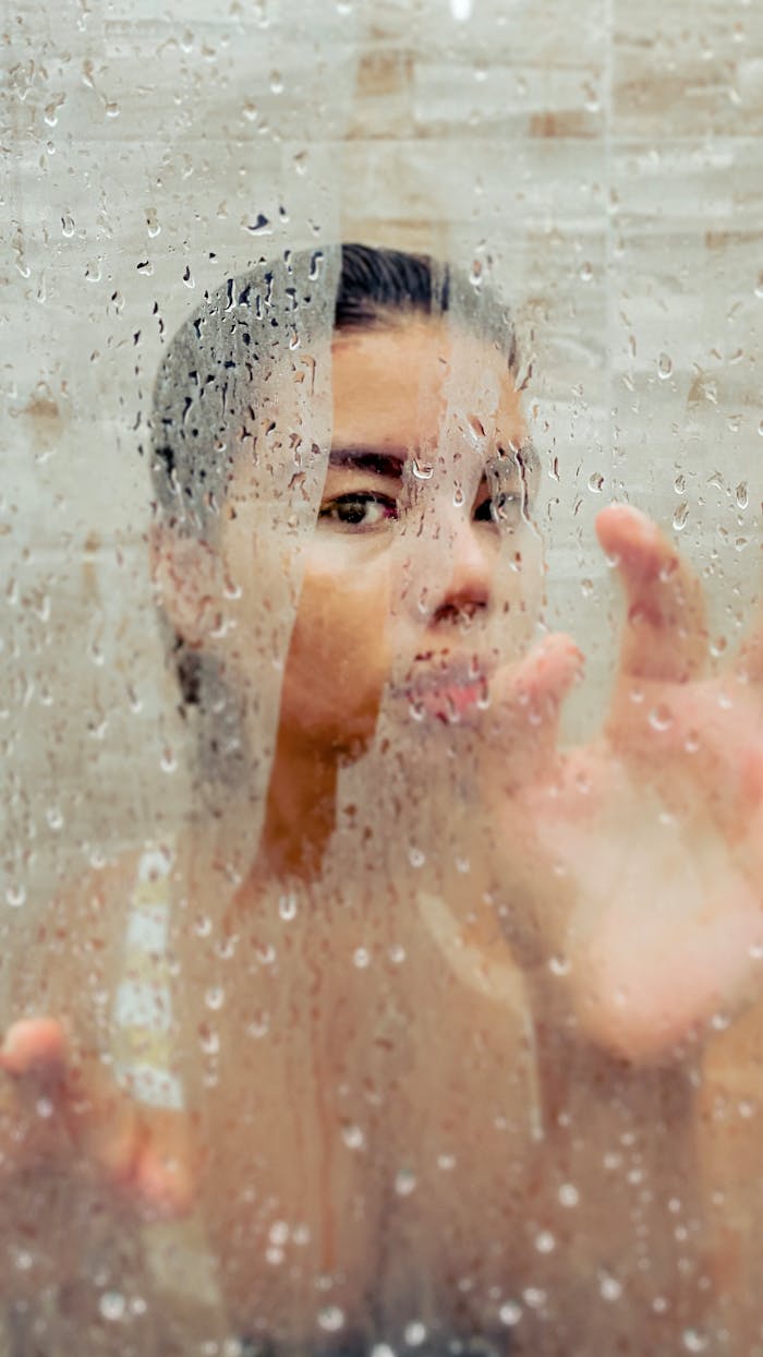 our-journey-01 A woman artistically captured behind a steamy shower glass indoors.