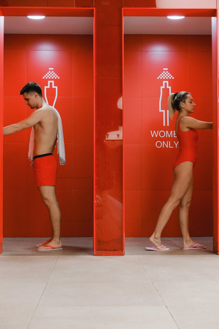 our-journey-03 A stylish red shower area with gender-specific signs and people in swimwear.